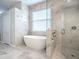 Modern bathroom showcasing a soaking tub, glass shower, and marble-look tiling at 3775 Brantley Place Cir, Apopka, FL 32703