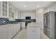 Bright kitchen with white cabinets, stainless steel appliances, and blue tile backsplash at 3842 Beacon Ridge Way, Clermont, FL 34711