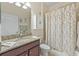 This cozy bathroom features a granite countertop, complementing the framed mirror and the shower with patterned curtains at 3948 Serena Ln, Clermont, FL 34711