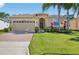 Charming single-story home with a brick driveway, lush lawn, and tropical landscaping at 3948 Serena Ln, Clermont, FL 34711