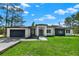 Charming single-story home featuring a manicured lawn, modern architectural design, and a spacious driveway with a two-car garage at 42191 Cashew St, Eustis, FL 32736