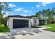 Side view of a modern home highlighting the dark garage door, a paved driveway, and lush landscaping at 42191 Cashew St, Eustis, FL 32736
