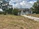 Quaint, one-story home featuring a concrete walkway and mature trees in the front yard at 447 E Desoto St, Clermont, FL 34711
