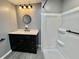 Bathroom with updated black vanity, a round mirror, and shower at 519 Hawthorne Blvd, Leesburg, FL 34748