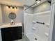 Bathroom with updated black vanity, a round mirror, and shower at 519 Hawthorne Blvd, Leesburg, FL 34748