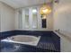 Bathroom featuring a tiled whirlpool tub and floral wallpaper at 5339 Kings Ct, Fruitland Park, FL 34731