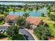 Stunning aerial view of townhomes with terracotta roofs overlooking a tranquil lake and lush green landscape at 5492 Compass Pt, Oxford, FL 34484