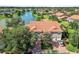 Aerial view showing a pond and the community of homes with terra cotta roofs at 5492 Compass Pt, Oxford, FL 34484