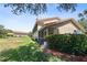 Rear exterior with manicured lawn, screened lanai, and attractive landscaping at 5492 Compass Pt, Oxford, FL 34484