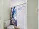 Bathroom with a toilet and shower with white tiles and a floral shower curtain at 5492 Compass Pt, Oxford, FL 34484