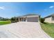 Beautiful home featuring a patterned driveway, well-manicured lawn, and lush landscaping at 560 Caputo Ct, The Villages, FL 32163
