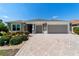 Inviting single-story home with a patterned driveway and beautiful landscaping at 560 Caputo Ct, The Villages, FL 32163