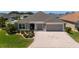 Single-story home showcasing a decorative driveway, manicured lawn, and a two-car garage at 560 Caputo Ct, The Villages, FL 32163