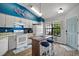 Kitchen with white cabinets, an island, modern appliances, wood floors, and bright blue accent wall at 579 Juniper Way, Tavares, FL 32778