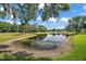 Picturesque pond surrounded by lush greenery and trees on a beautiful, sunny day with a blue sky at 579 Juniper Way, Tavares, FL 32778