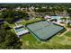 Aerial view of shuffleboard and tennis courts offering residents recreational activities, with green spaces and manicured landscaping at 5818 Greenbriar Loop, Leesburg, FL 34788