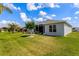 Landscaped backyard with a screened lanai, green lawn, young trees, and well-maintained exterior at 5818 Greenbriar Loop, Leesburg, FL 34788