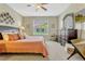 Cozy bedroom features a ceiling fan, neutral walls, dresser with a mirror, and comfortable seating area at 5818 Greenbriar Loop, Leesburg, FL 34788