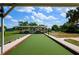 View of the outdoor bocce ball courts featuring covered seating areas set amidst lush greenery and a beautiful blue sky at 5818 Greenbriar Loop, Leesburg, FL 34788