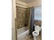Bathroom featuring a shower-tub combo with neutral tile and a toilet, showcasing essential amenities at 604 N Old Wire Rd, Wildwood, FL 34785