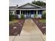 Inviting covered front porch with blue accents and concrete walkway leading to the entrance at 604 N Old Wire Rd, Wildwood, FL 34785