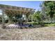Backyard patio featuring a pergola and a dining area with seating surrounded by green vegetation at 616 Third Ave, Lady Lake, FL 32159