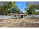 Back of home with a large backyard with a white picket fence and mature trees in a rural setting at 6808 Fern Cir, Leesburg, FL 34748