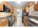 Modern kitchen with stainless steel appliances, wood cabinets, and tile flooring at 6808 Fern Cir, Leesburg, FL 34748