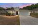 Charming single-story home with a well-manicured front yard, a two-car garage, and a welcoming entrance at dusk at 704 Chelsea Ave, Fruitland Park, FL 34731
