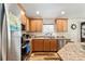 Well-lit kitchen with stainless steel appliances, wood cabinets, and beautiful countertops at 704 Chelsea Ave, Fruitland Park, FL 34731