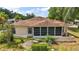 Back of home featuring a screened-in lanai with a bench and manicured landscaping at 705 Grand Vista Trl, Leesburg, FL 34748