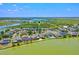 An aerial view showcases lakefront neighborhood with homes and lush greenery around a lake at 722 Barefoot Bay Loop, Groveland, FL 34736
