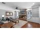 Cozy living room featuring a stone fireplace, a ceiling fan, built-in shelves, and hardwood floors at 722 Barefoot Bay Loop, Groveland, FL 34736