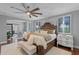 Bright main bedroom boasts hardwood floors, large bed, windows, and unique ceiling fan at 722 Barefoot Bay Loop, Groveland, FL 34736