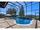 Stunning pool with waterfall feature, surrounded by a screened enclosure and lush landscaping at 722 Barefoot Bay Loop, Groveland, FL 34736