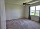 Carpeted bedroom features a ceiling fan and a large window with curtains at 7974 Penrose Pl, Wildwood, FL 34785