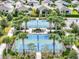 Aerial view of tennis and pickleball courts surrounded by lush landscaping and palm trees in a quiet neighborhood at 7974 Penrose Pl, Wildwood, FL 34785