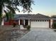 Charming red home with solar panels, a two-car garage, and well-maintained landscaping at 808 Chamberlain Loop, Lake Wales, FL 33853