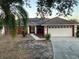 Charming red home with solar panels, a two-car garage, and well-maintained landscaping at 808 Chamberlain Loop, Lake Wales, FL 33853