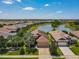 Aerial view of house showcasing well-manicured lawn, landscaping, paver driveway, and tranquil lake at 8387 Bridgeport Bay Cir, Mount Dora, FL 32757