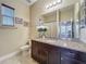 Well-lit bathroom features granite countertop vanity with dark wood cabinets, a mirror, and tan colored walls at 8387 Bridgeport Bay Cir, Mount Dora, FL 32757