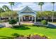 Inviting clubhouse exterior featuring a covered entrance, meticulous landscaping, and mature palm trees at 8387 Bridgeport Bay Cir, Mount Dora, FL 32757