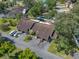 Aerial view of the property surrounded by lush trees in a community setting, with a driveway and street visible at 903 Belle Oak Dr, Leesburg, FL 34748