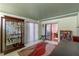 Bonus room/office with sliding door exit to backyard, display cabinet and red rug over tile floor at 903 Belle Oak Dr, Leesburg, FL 34748