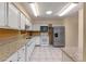 Well-lit kitchen featuring white cabinetry, stone countertops and stainless steel appliances at 903 Belle Oak Dr, Leesburg, FL 34748