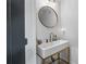 Modern powder room showcasing a sleek vanity with brass fixtures, a round mirror, and designer accents at 9134 Mossy Oak Ln, Clermont, FL 34711