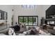 This living room features a modern fireplace, large windows with backyard views, and seamless access to the outdoor pool area at 9134 Mossy Oak Ln, Clermont, FL 34711