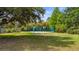 Backyard sport court surrounded by trees and lush landscaping at 9134 Mossy Oak Ln, Clermont, FL 34711