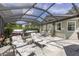 A screened-in back patio with a hot tub, stone flooring, and lounge chairs provides a relaxing outdoor living space at 923 Oleander St, The Villages, FL 32159