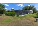 Landscaped backyard featuring a screened-in lanai, patio seating, and lush greenery at 923 Oleander St, The Villages, FL 32159